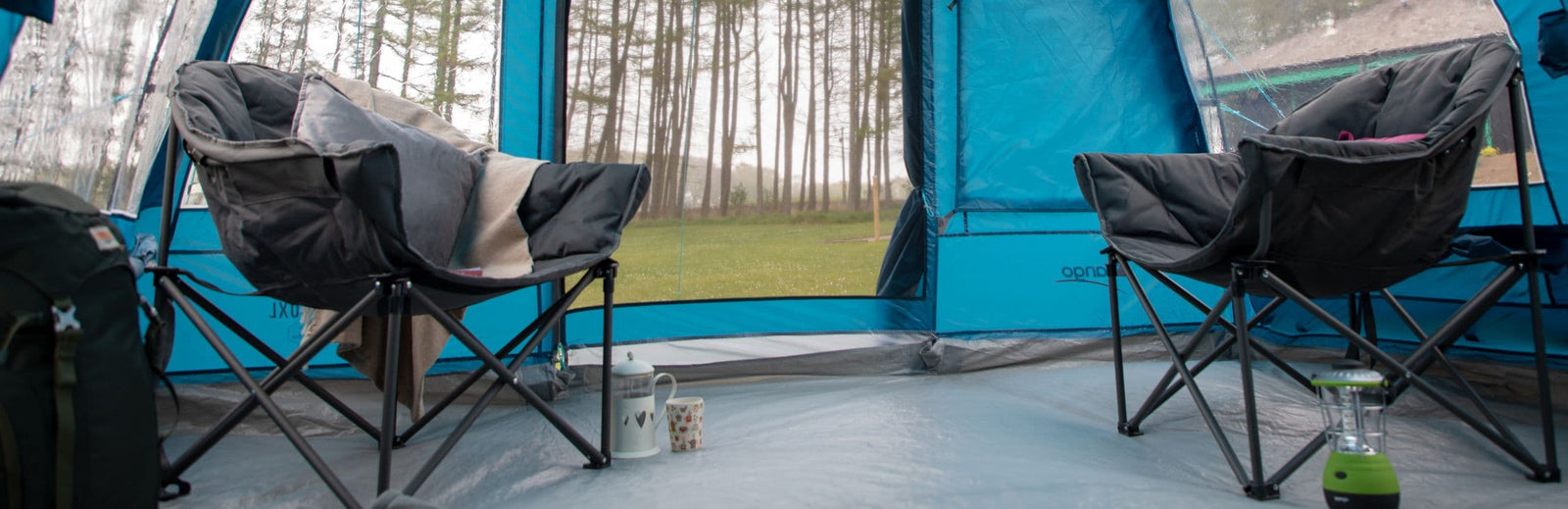 Vango Titan 2 Chair positioned outside a tent, featuring a book and blanket for added comfort, highlighting its 180kg max load.