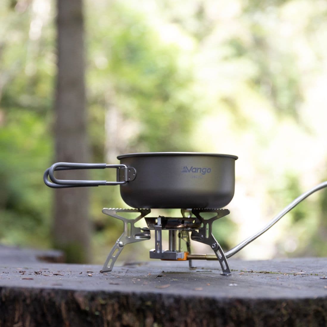 Close-up of the Vango Titanium 2 Piece Cook Set on a gas stove in a natural outdoor setting, ideal for camping and backpacking.