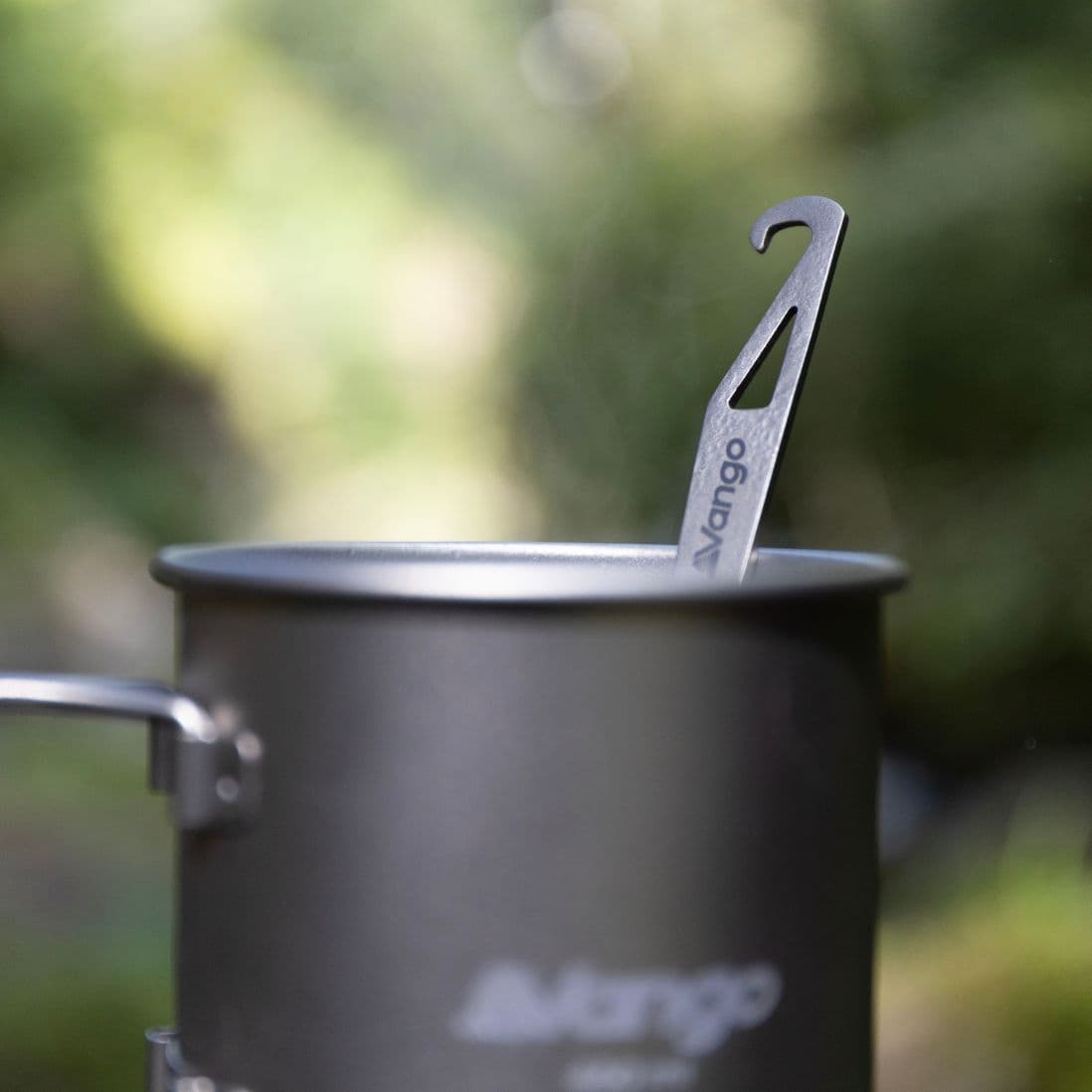 Close-up of Vango Titanium Spork with opener resting inside a Vango camping mug, compact camping cutlery for outdoor meals.