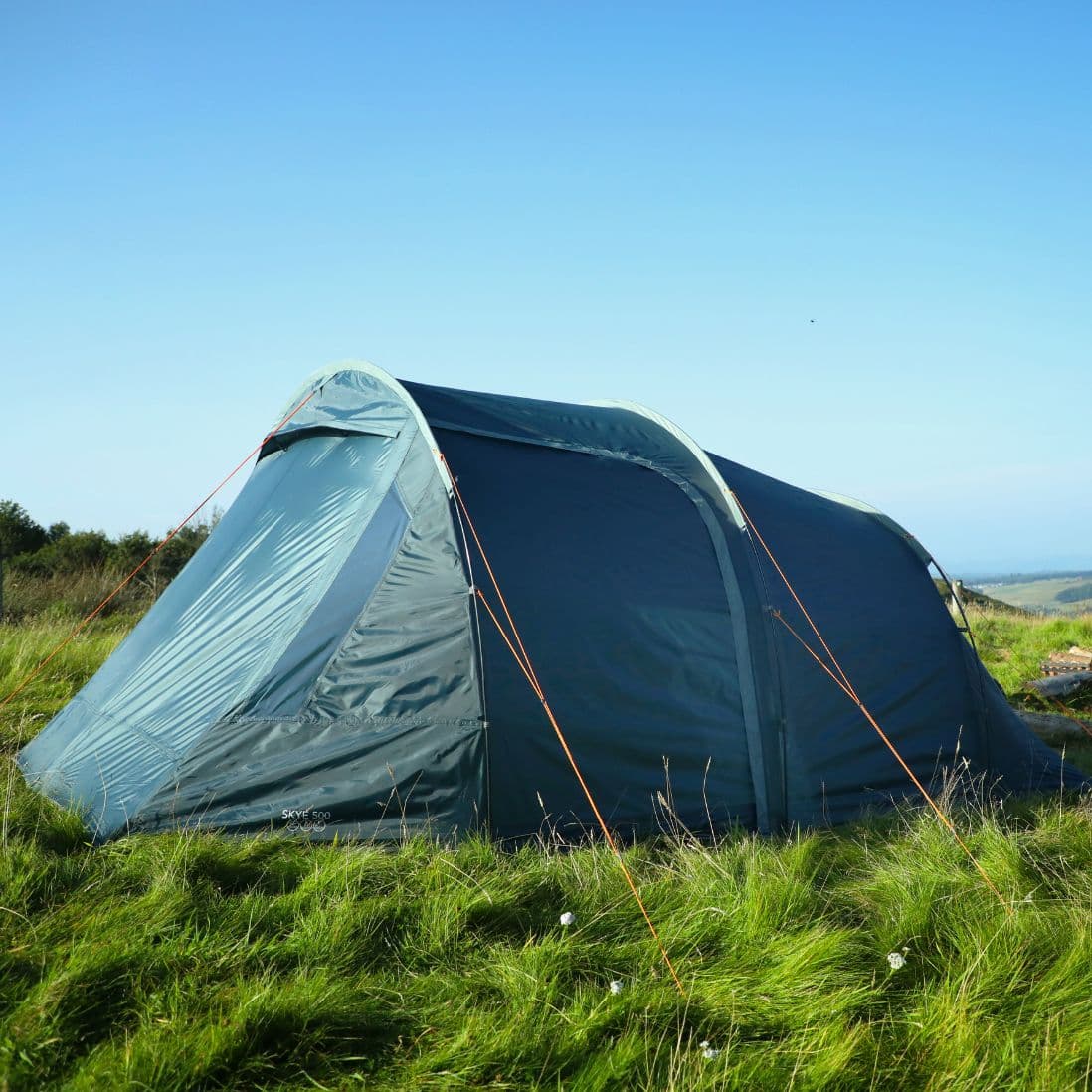 Side view of the Vango Skye 500 tent set up at a festival campsite, highlighting its durable structure and ample room for five people.