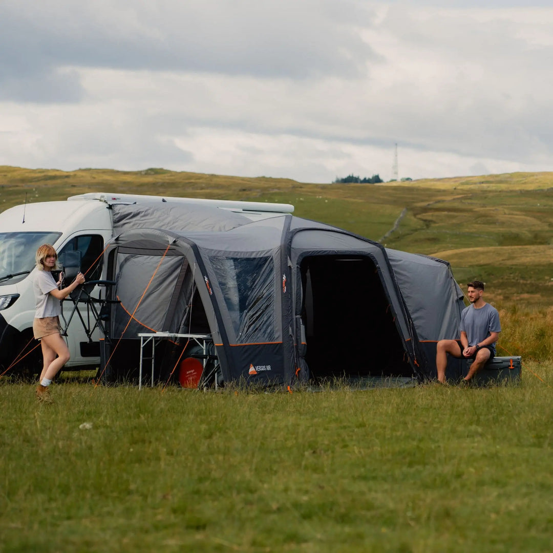 Spacious Vango Versos Air Mid awning attached to a campervan, providing a comfortable outdoor shelter for relaxing in a scenic field.