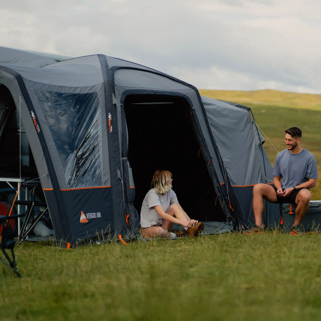 A woman and man conversing outside the Vango Versos Air Mid awning, highlighting its easy-access entrance and durable weatherproof fabric.