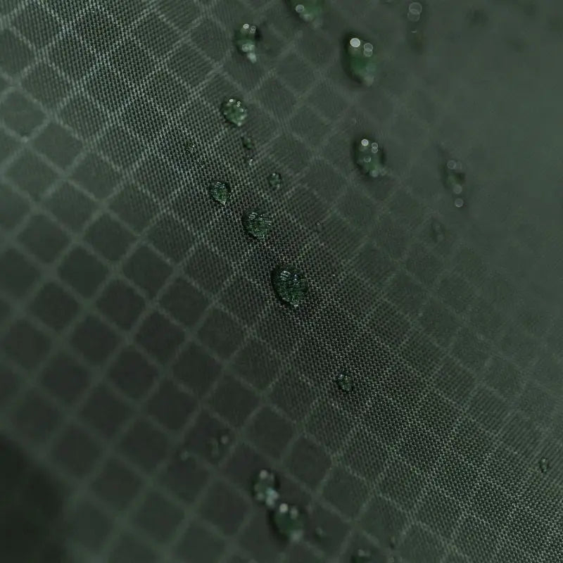 Close-up of a textured green fabric surface with water droplets. Showing tents' waterproofing abilities.