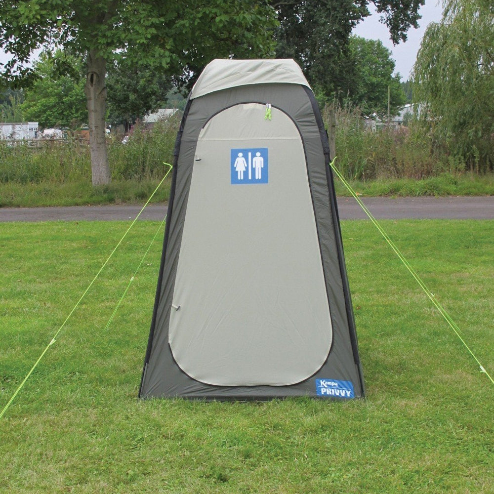 A gray Kampa Privvy Toilet Tent set up on grass, with a sign depicting a restroom symbol on the front.